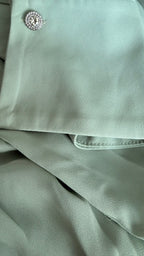 Close-up of light green fabric with a button on a gray background