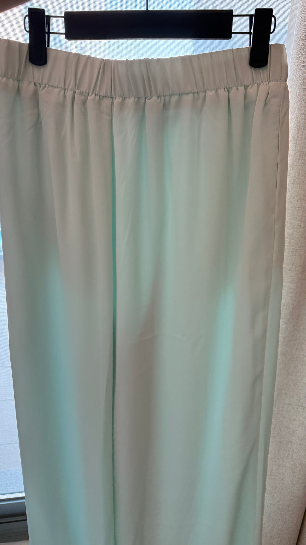 Beige curtain hanging on a rod with a blurred background