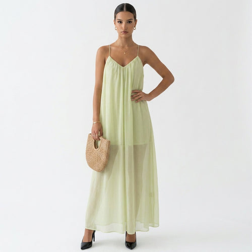 Woman wearing a light green dress holding a straw bag on a white background