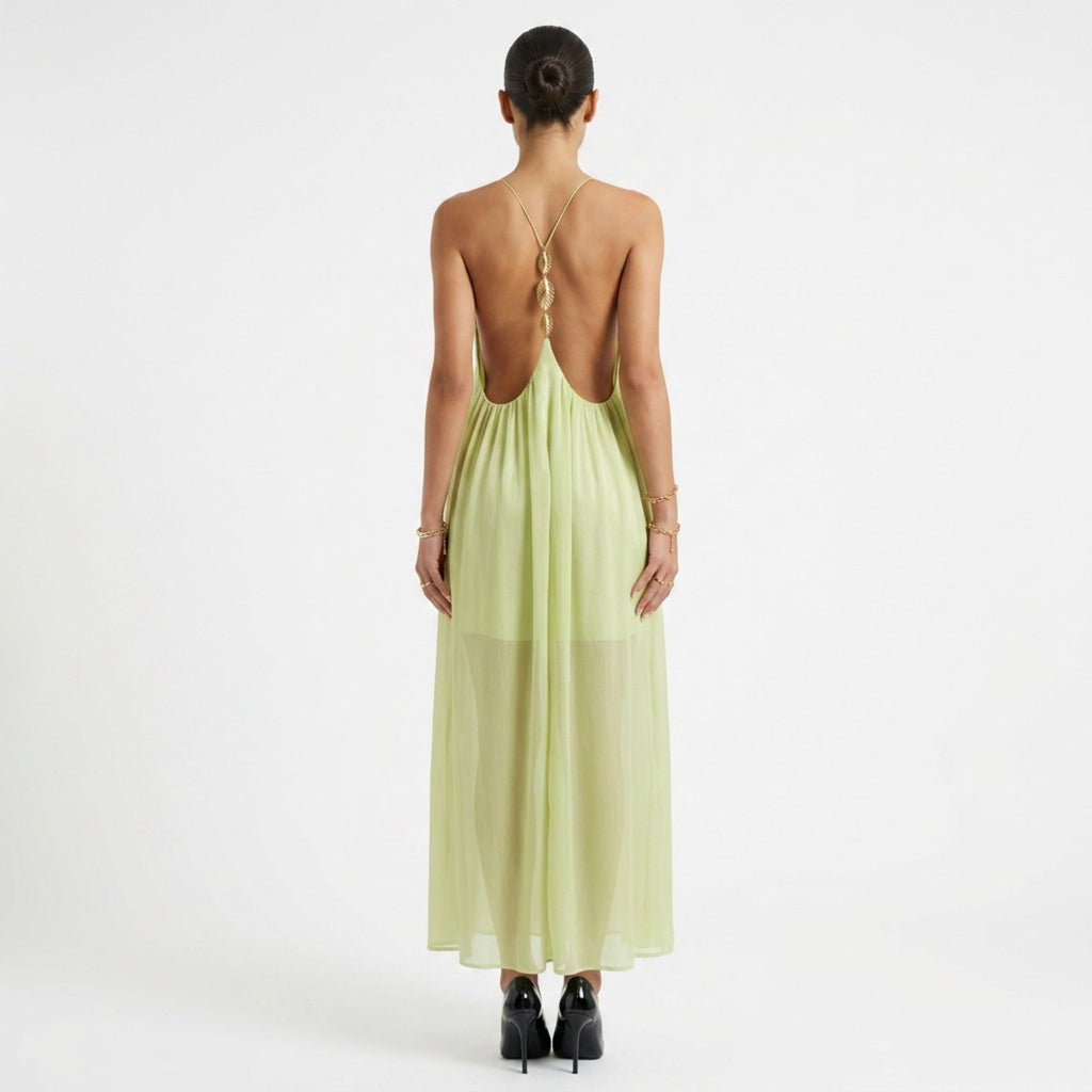 Woman wearing a light green dress with an open back on a white background