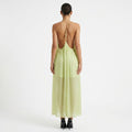 Woman wearing a light green dress with an open back on a white background