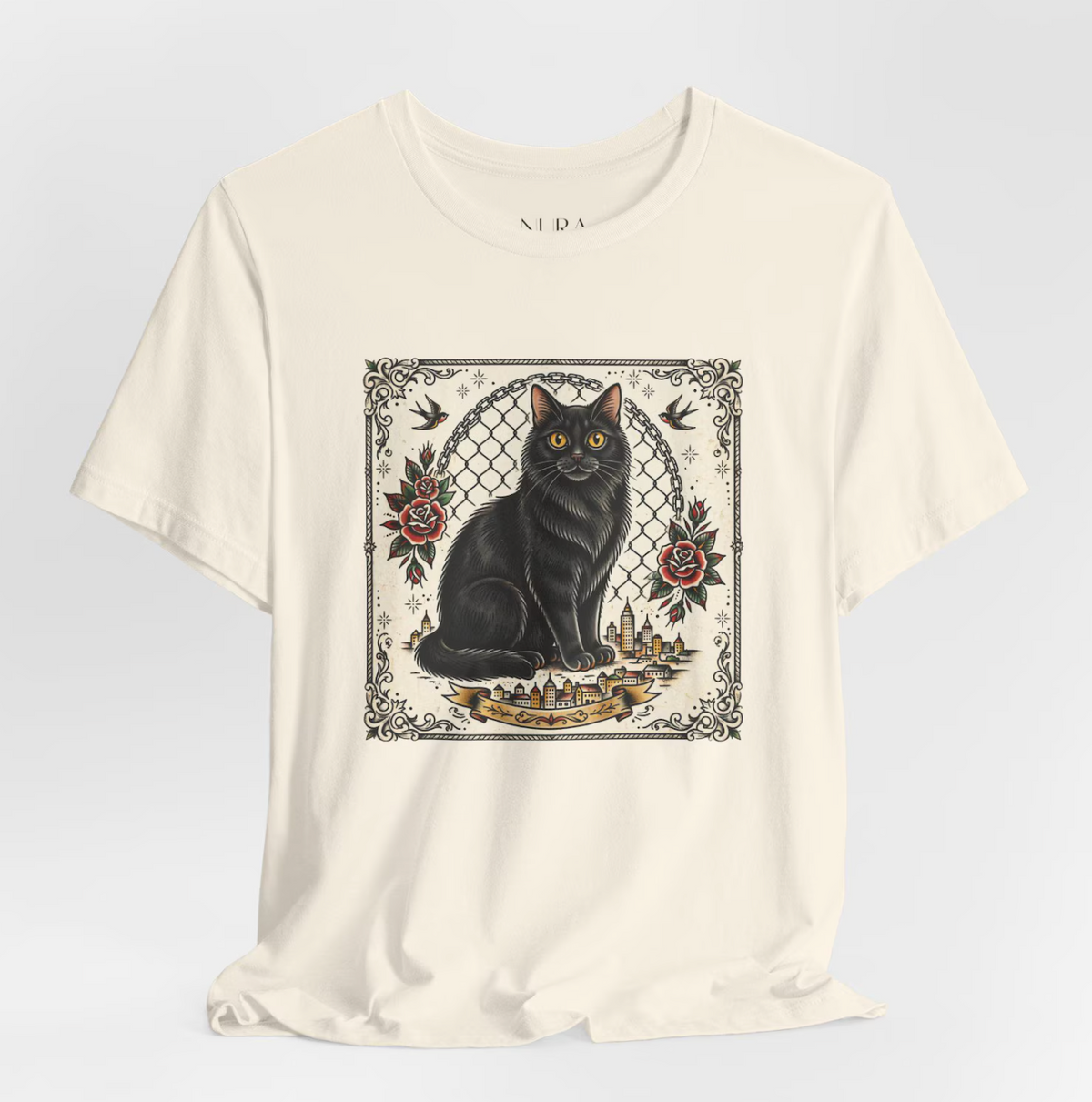 An off-white short-sleeve t-shirt with a central graphic print of a black cat sitting in front of a chain-link fence, surrounded by red roses and birds, on a light gray background.