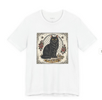 A white short-sleeve crewneck t-shirt featuring a central graphic print of a black cat sitting in front of a chain-link fence, decorated with red roses and a gold crown.