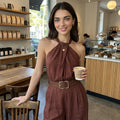 Woman in a brown dress holding a coffee cup in a cafe
