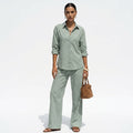 Woman wearing a light green outfit with a brown bag on a white background