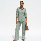 Woman wearing a light green outfit with a brown bag on a white background