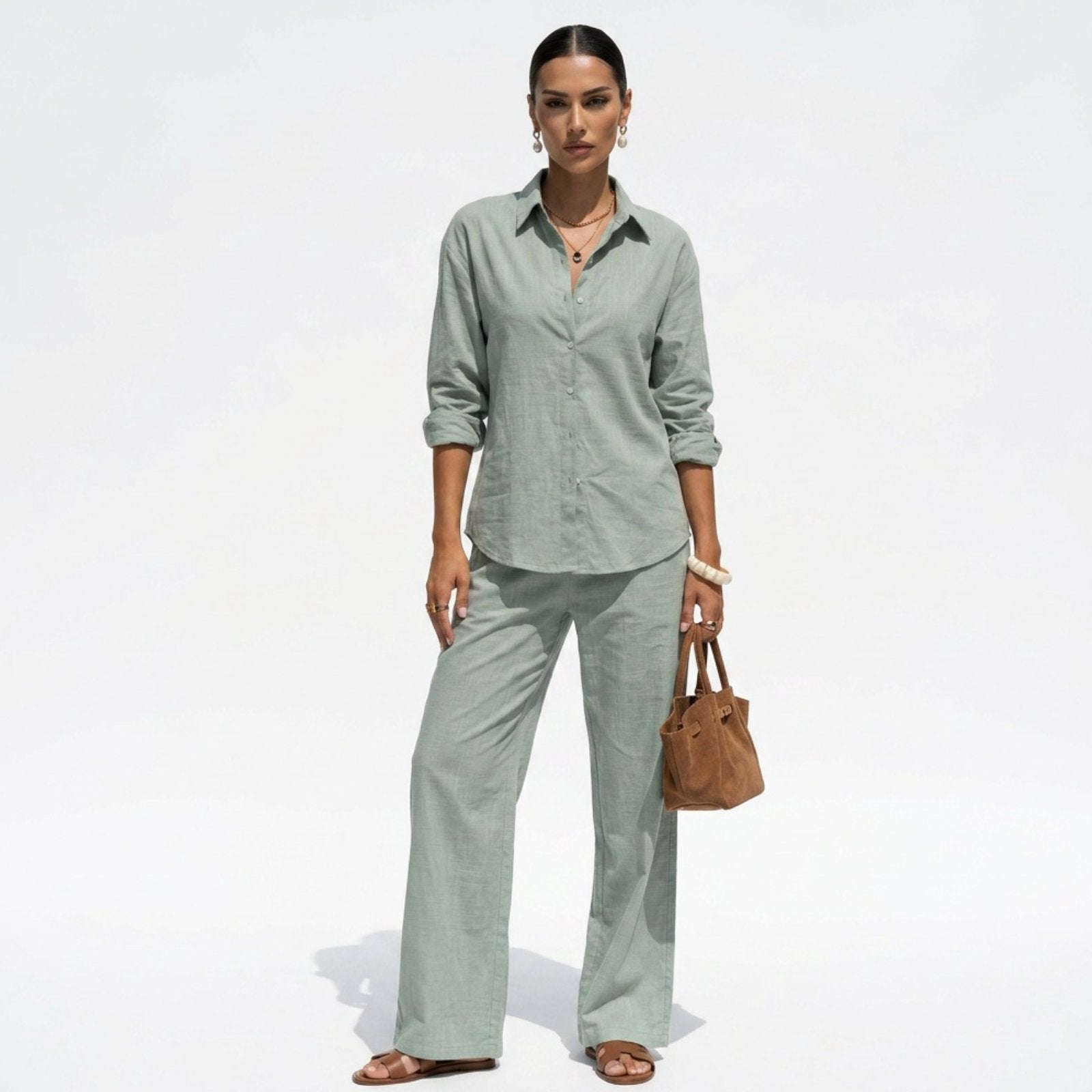 Woman wearing a light green outfit with a brown bag on a white background