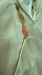 Gold necklace with leaf-shaped pendants on a light fabric background
