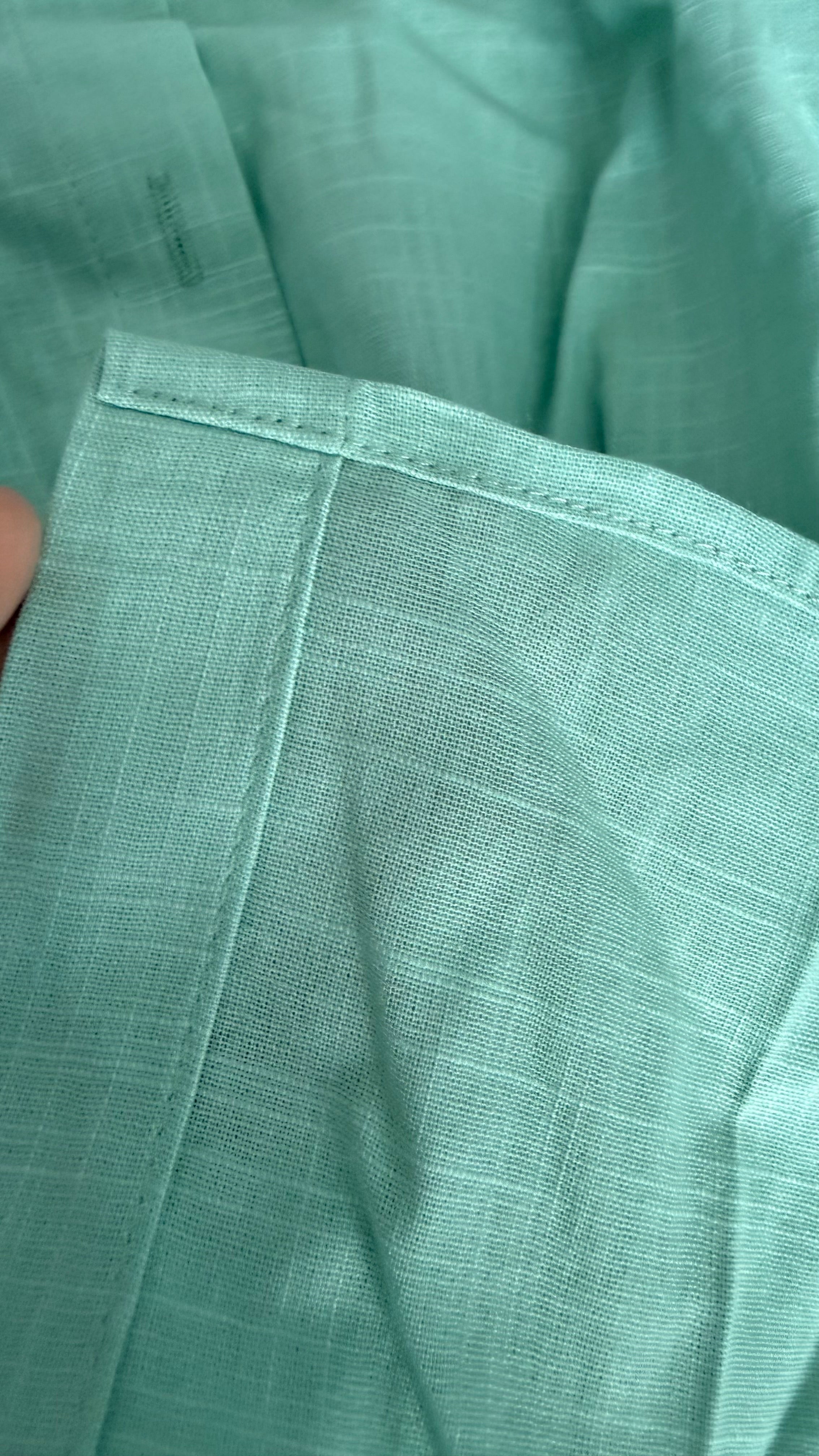 Close-up of teal fabric with a visible seam