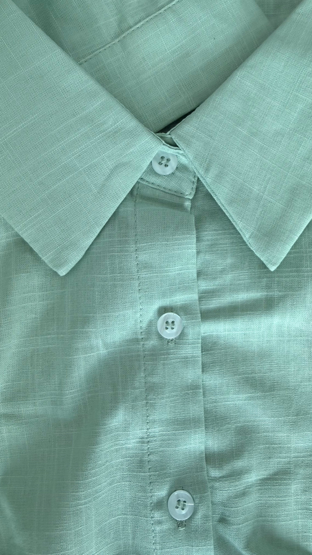 Close-up of a light green shirt with buttons