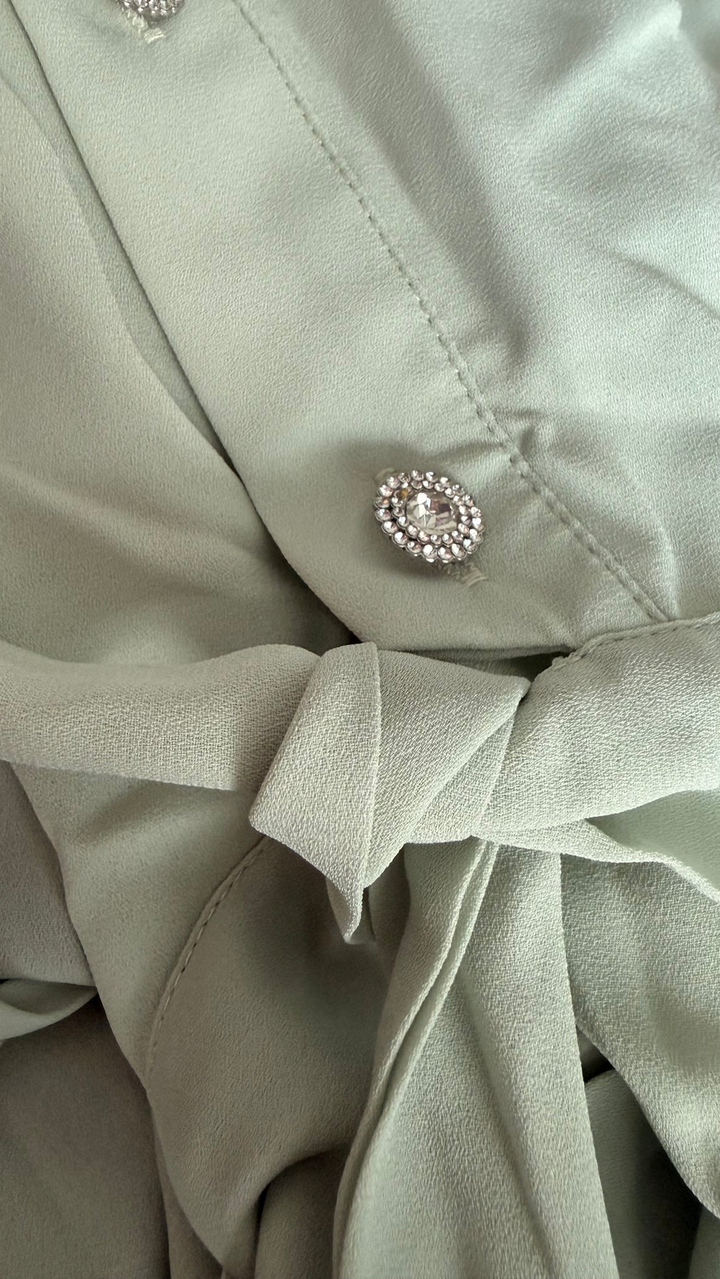 Close-up of a light green fabric with a decorative button.