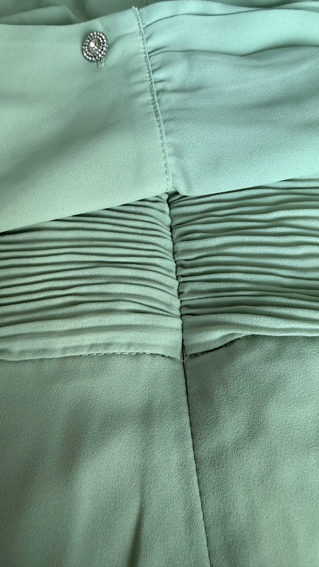 Close-up of light green fabric with a button detail