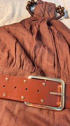 Brown fabric with a leather belt and metal buckle on a textured surface