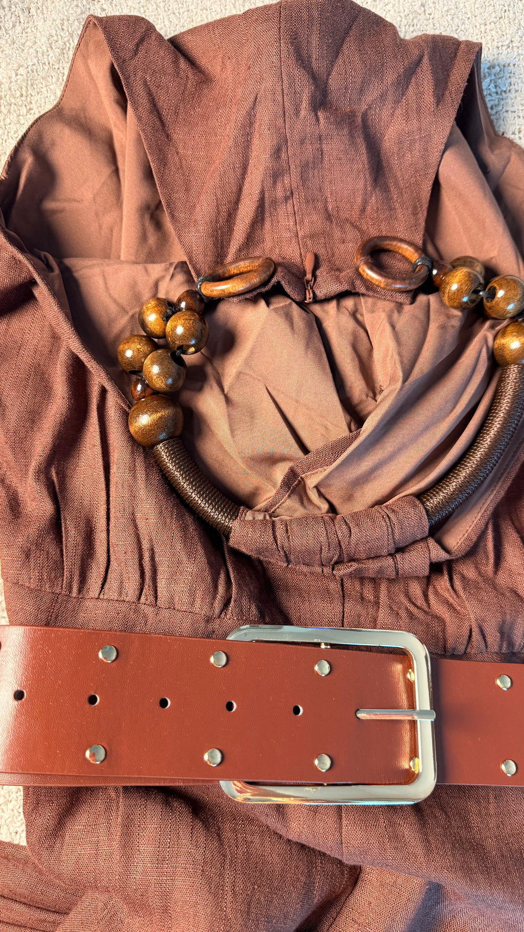 Brown fabric with a belt and decorative elements on a neutral background