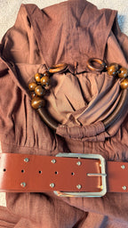 Brown fabric with a belt and decorative elements on a neutral background