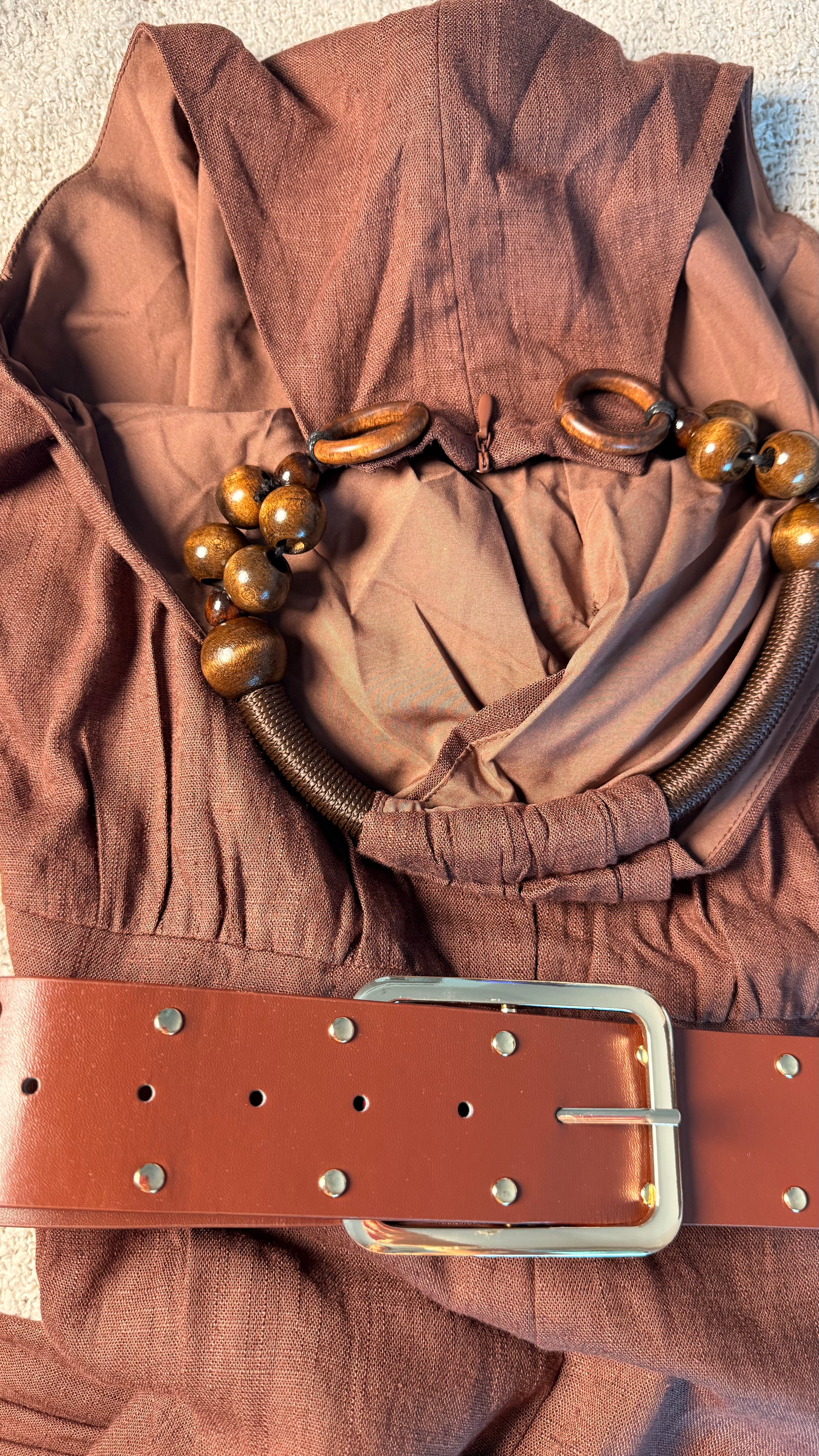 Brown fabric with a belt and decorative elements on a neutral background