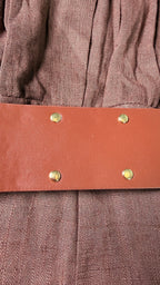 Brown leather belt with gold studs on a brown fabric background