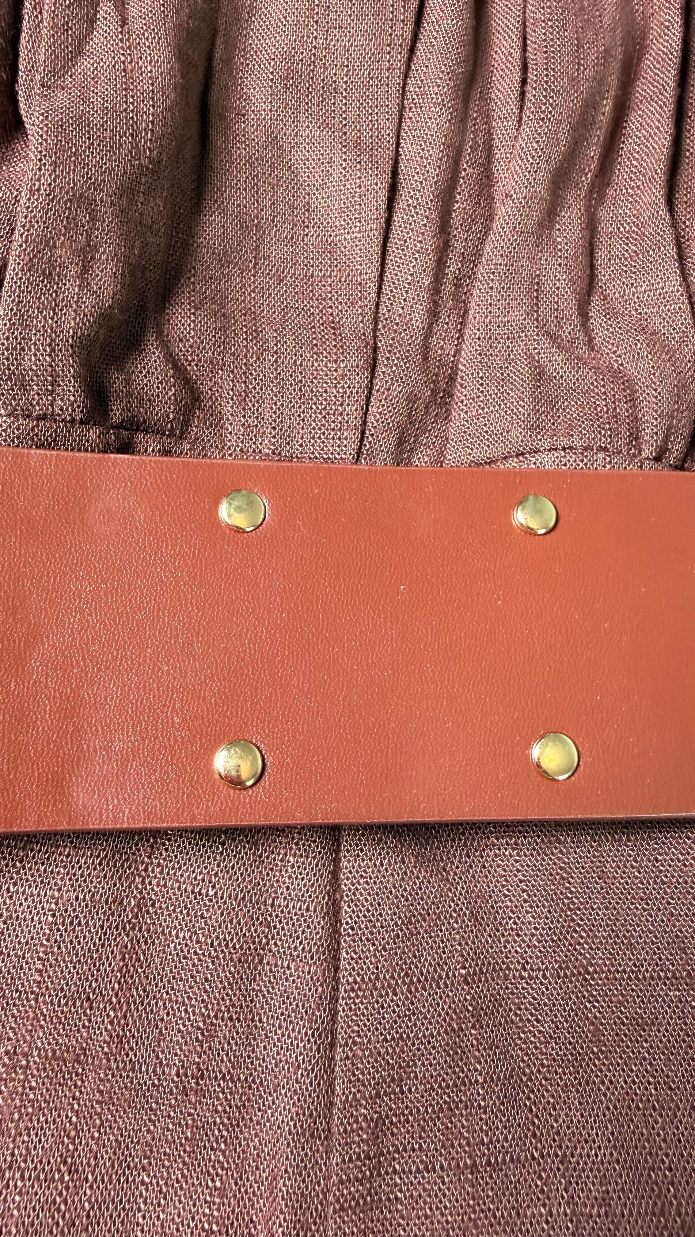 Brown leather belt with gold studs on a brown fabric background