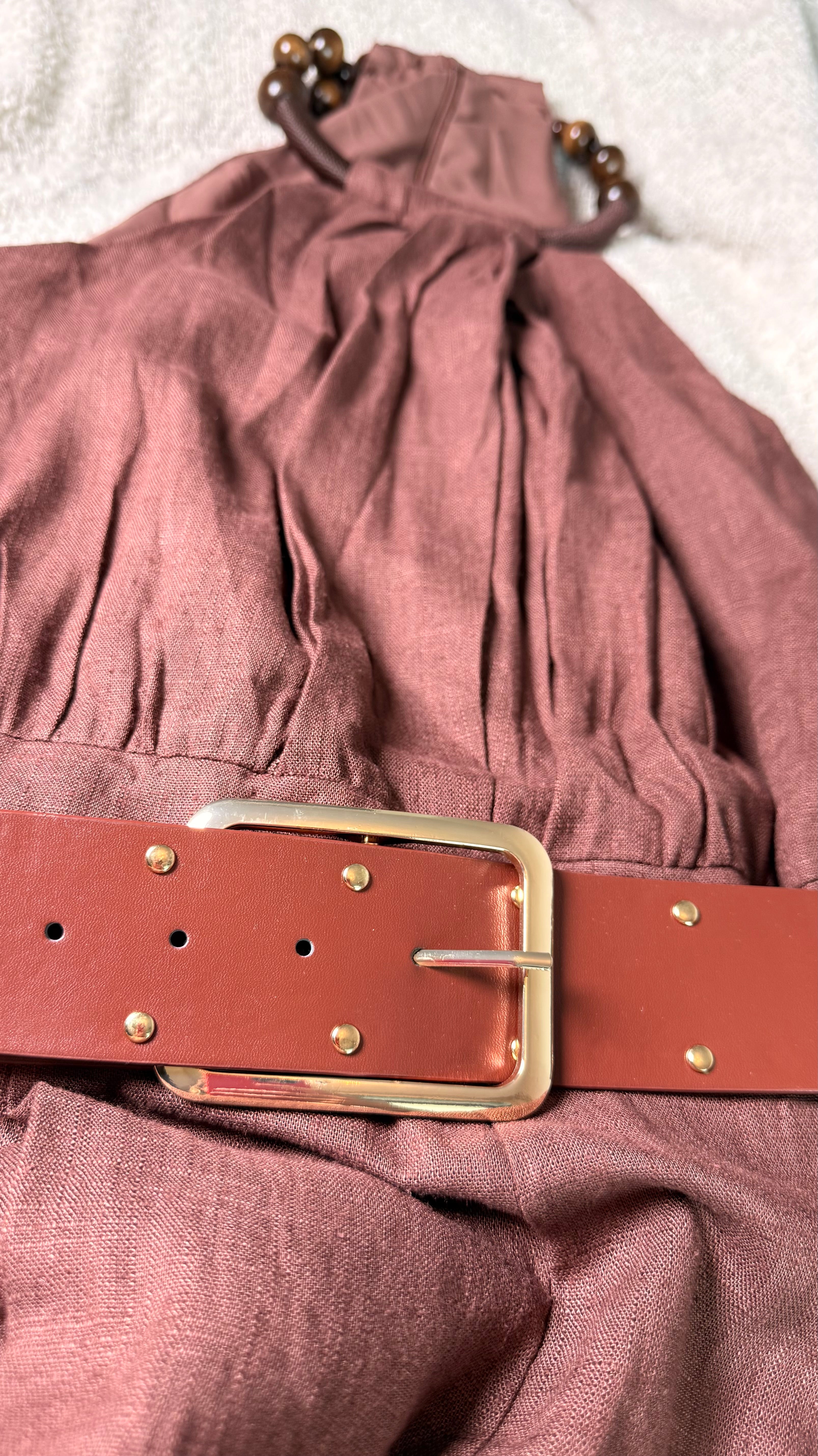 Mauve dress with a red belt and gold buckle on a light background