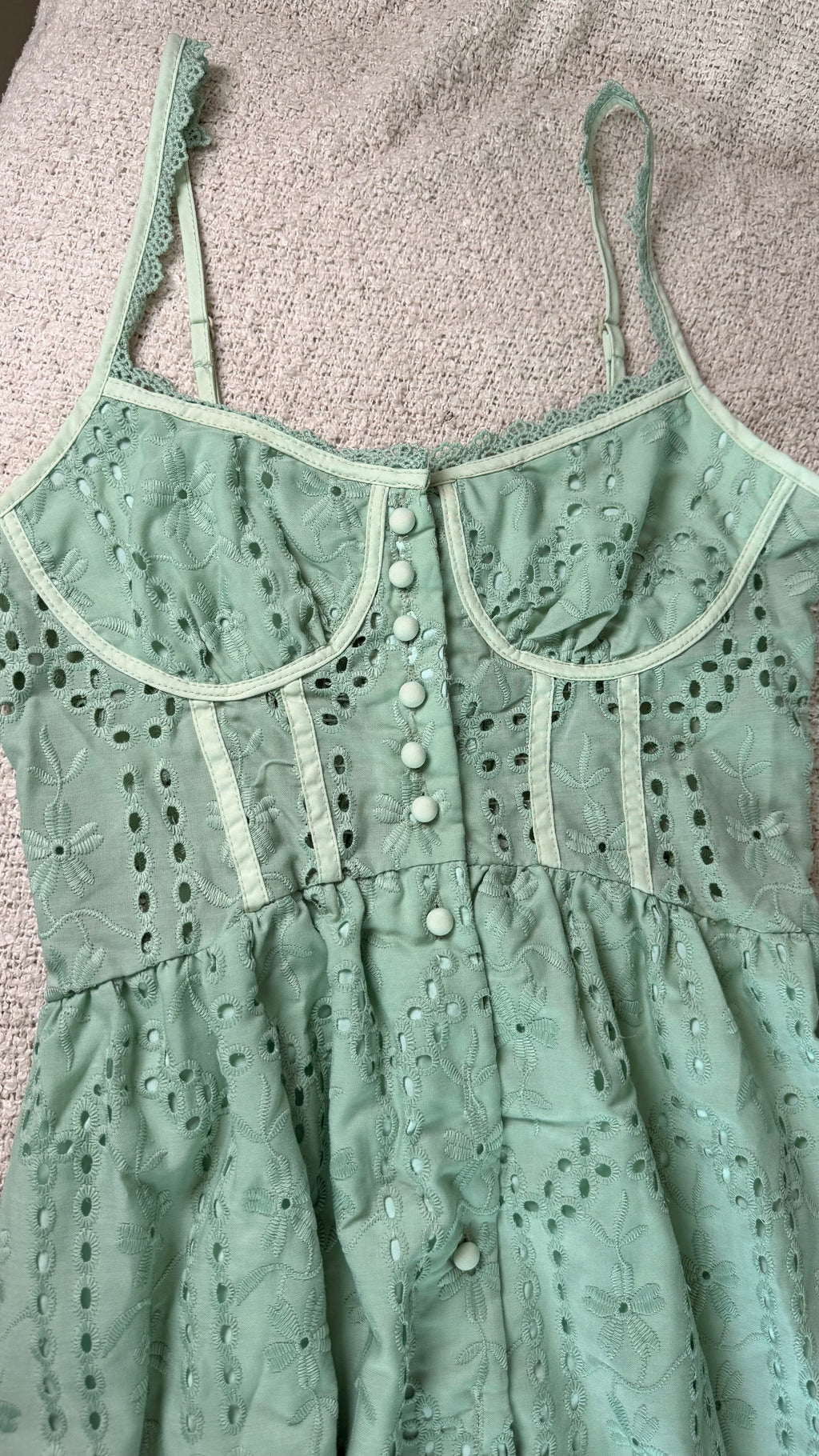 Green lace dress with button details on a textured surface