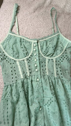 Green lace dress with button details on a textured surface