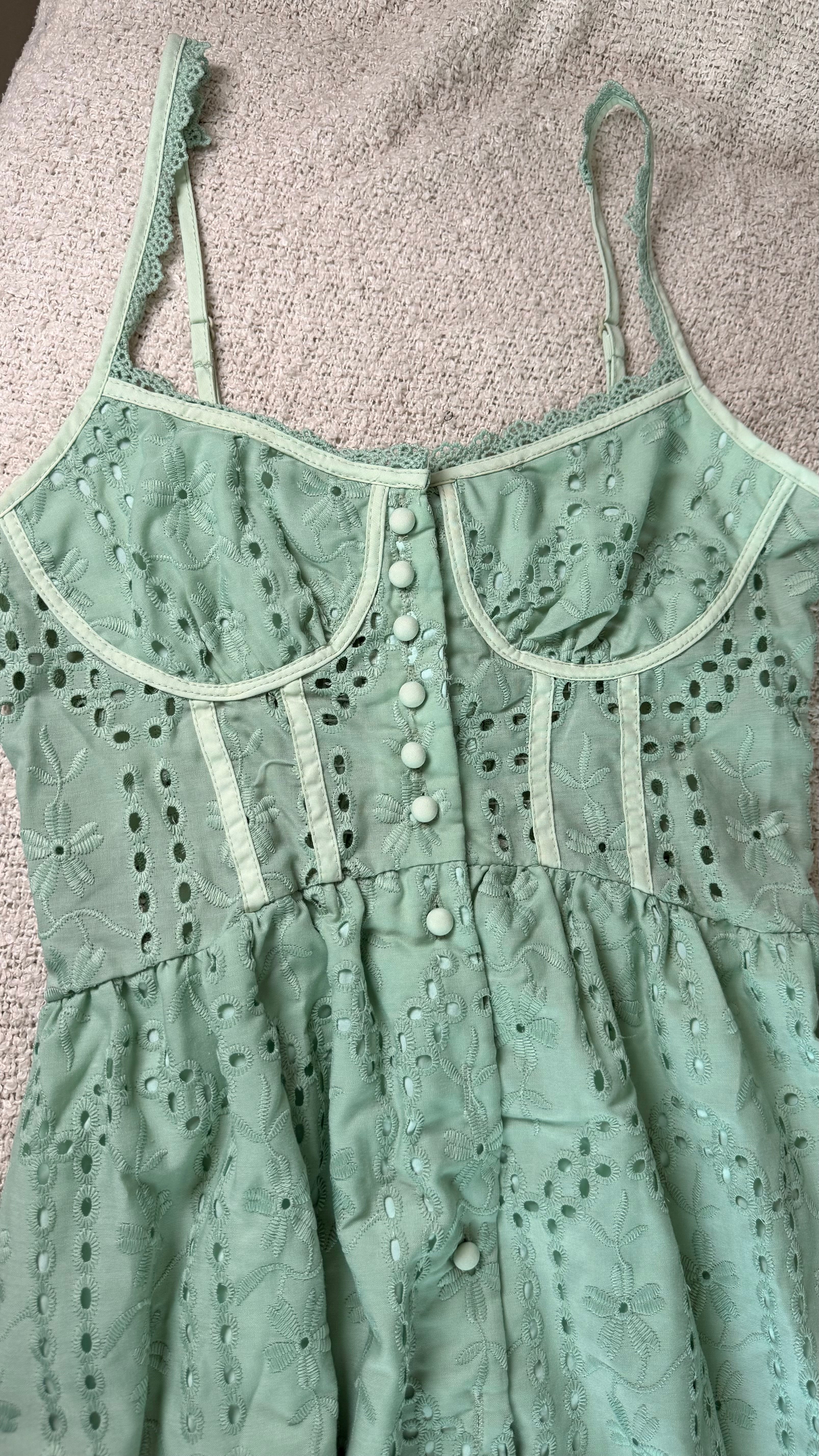 Green lace dress with button details on a textured surface