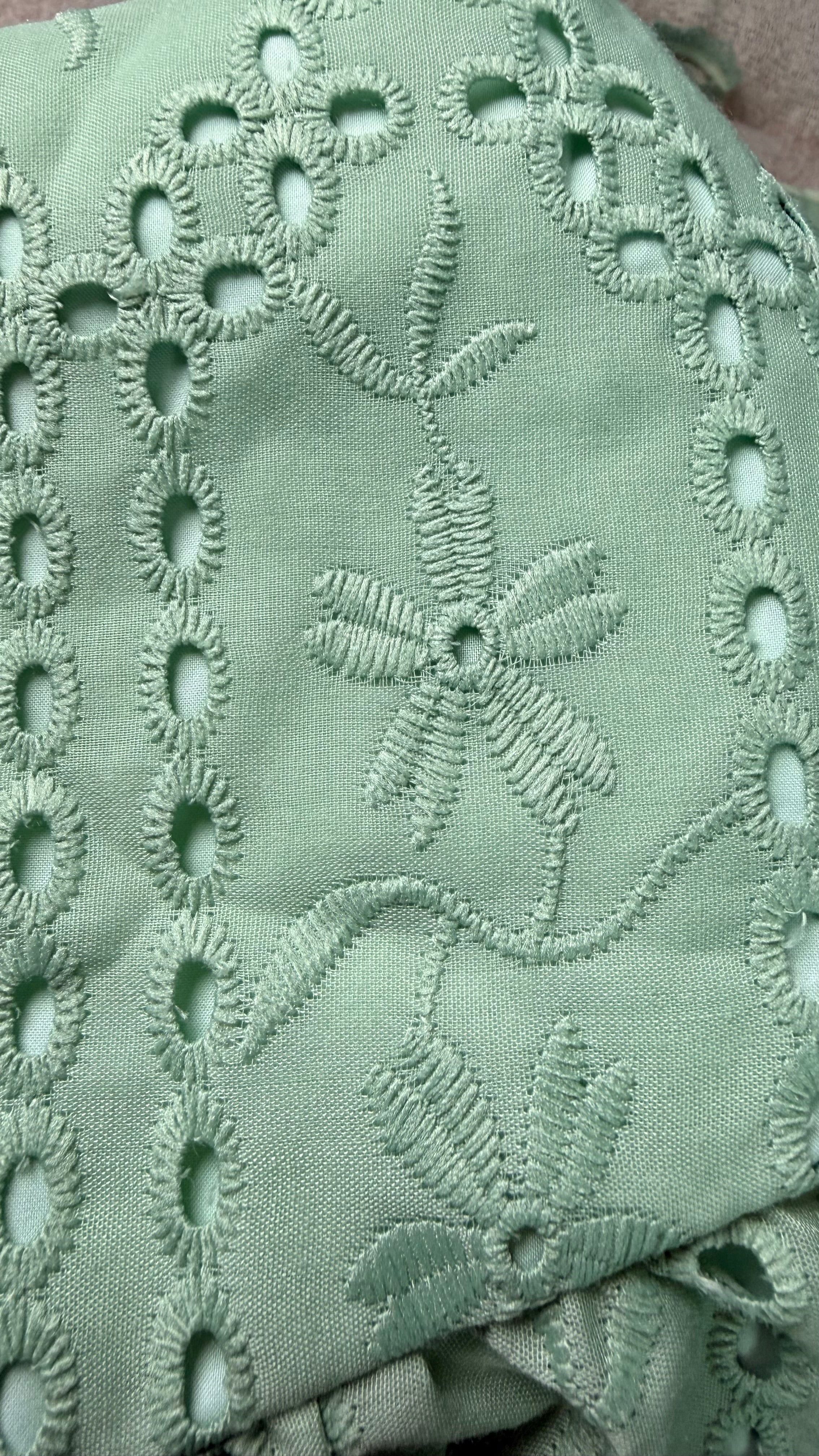 Close-up of green fabric with intricate embroidery