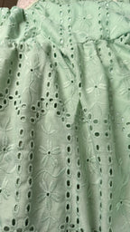 Close-up of light green lace fabric with floral patterns