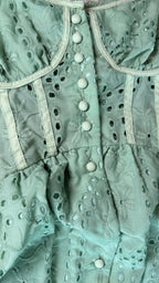 Close-up of a light green lace garment with button details