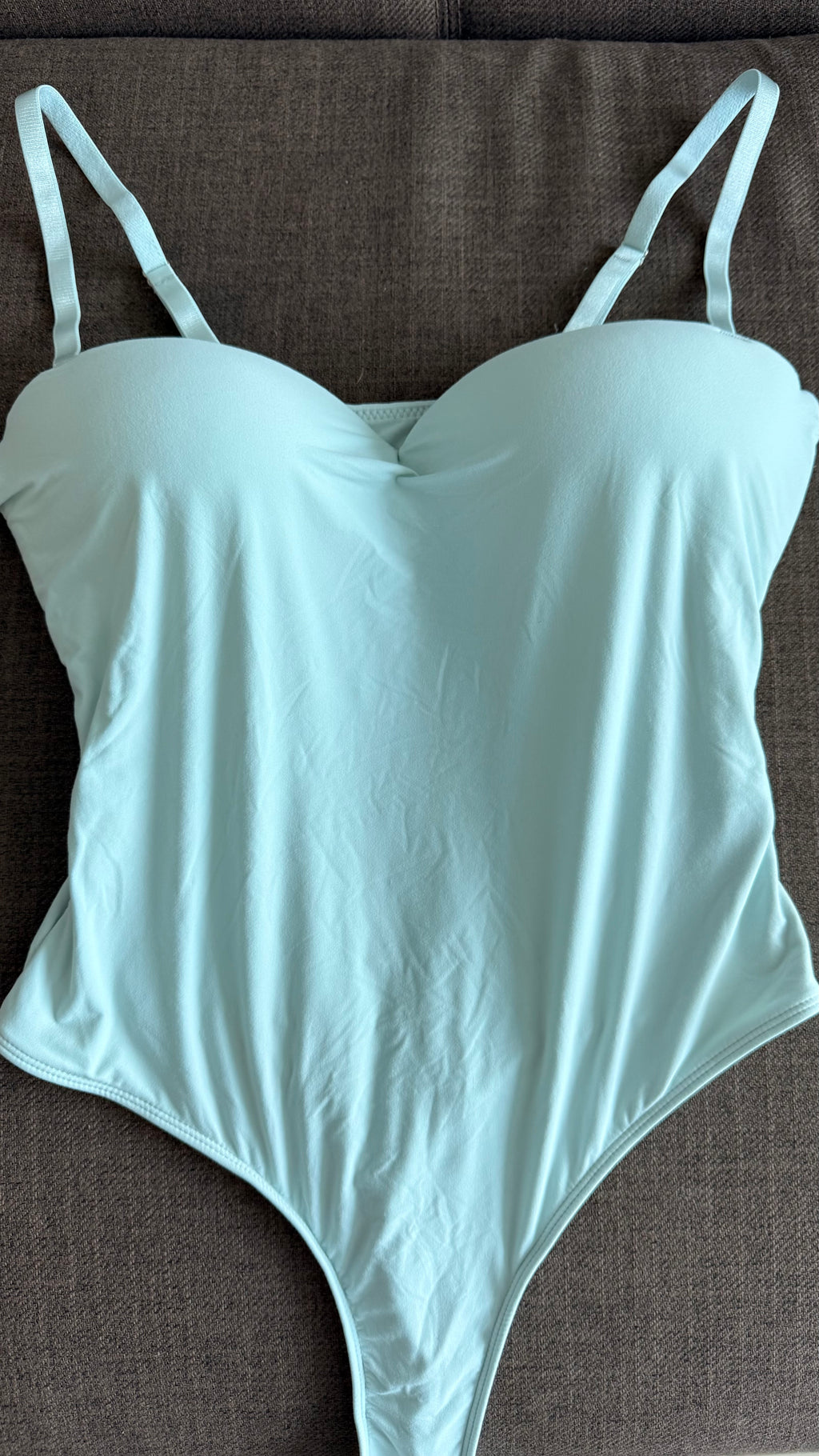 Light green bodysuit on a brown surface