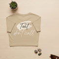 Beige t-shirt with 'Text don't call' text on a light wooden surface with decorative items.