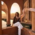 Woman sitting by a pool with a scenic sunset in the background