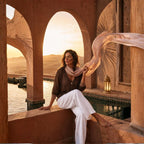 Woman sitting by a pool with a scenic sunset in the background