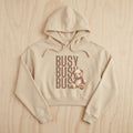 Beige hoodie with teddy bear and 'BUSY BUSY BUS' text on a wooden surface